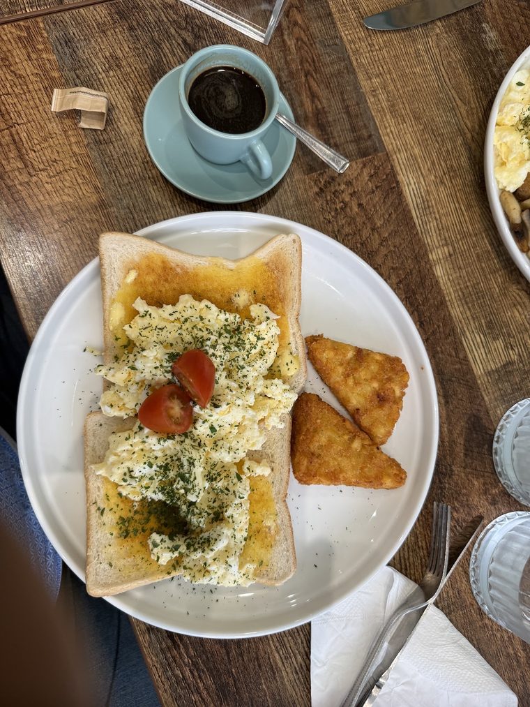 Scrambled egg on toast with tomatoes, herbs and a hash brown