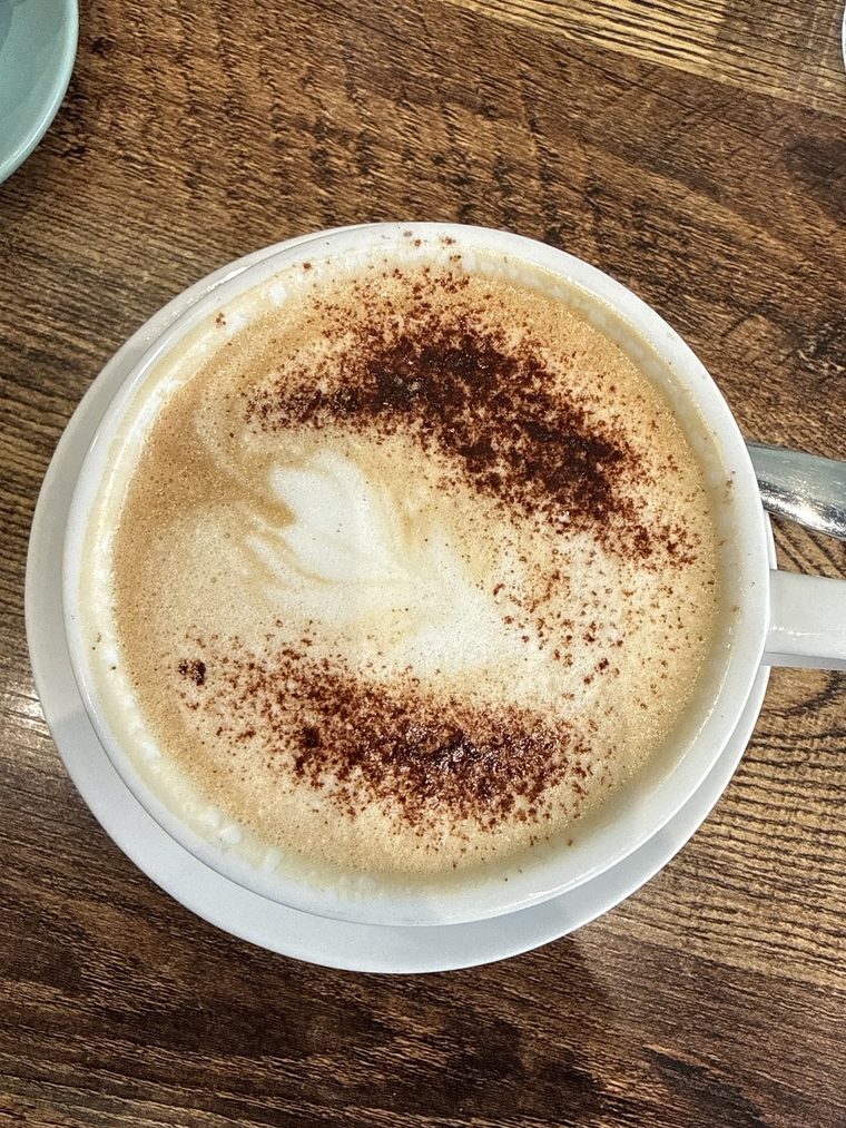 Cappuccino with latte art and chocolate dusting on a wooden table