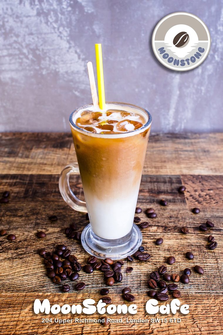 Layered iced latte in a tall glass with a yellow straw (crop out the branding band)