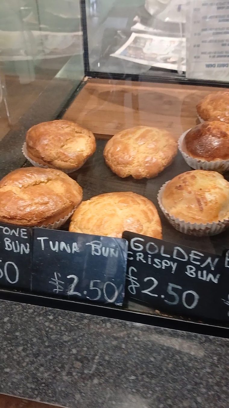 Golden baked buns in the counter display cabinet (crop above the chalkboard so no lettering shows)