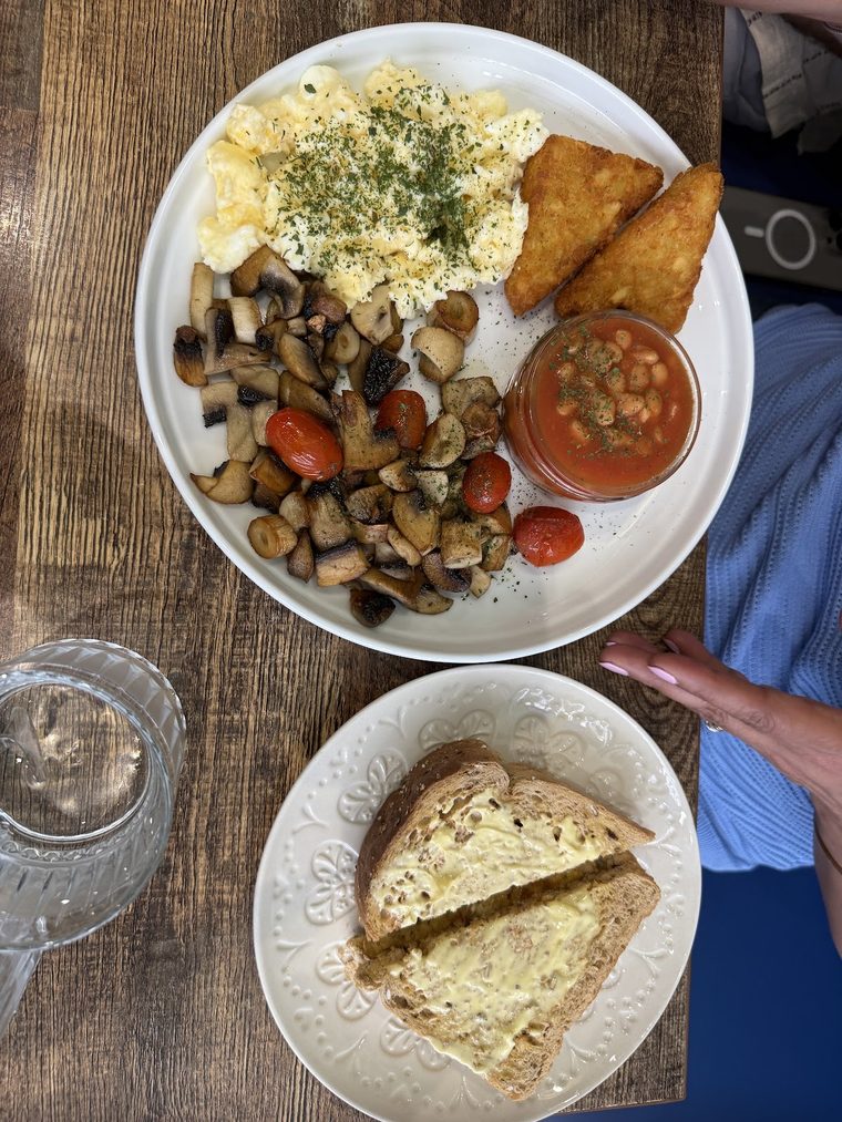 Breakfast plate of scrambled egg, mushrooms, hash brown, tomatoes and beans with cheese on toast